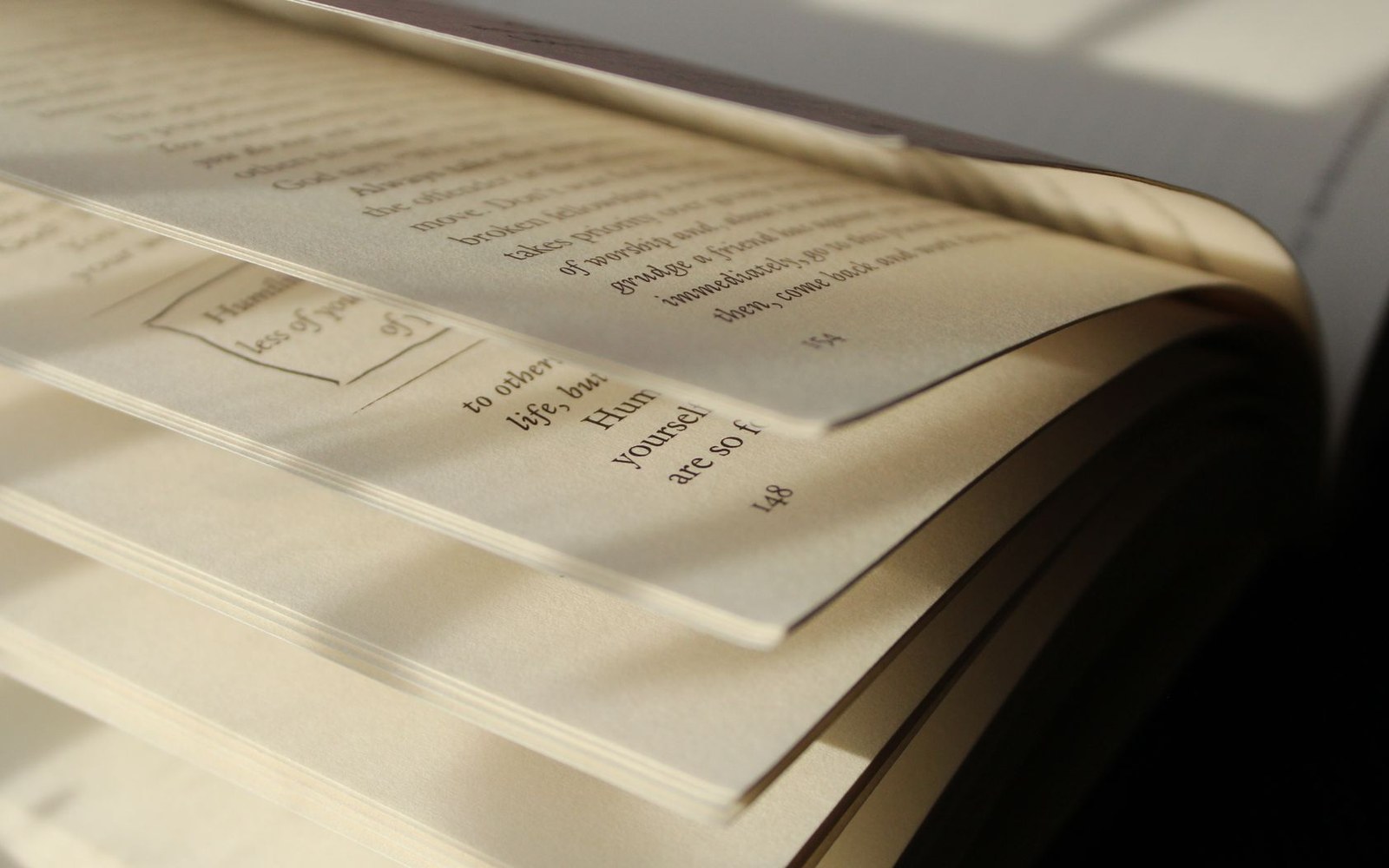 An uncut French paperback open to its first folded signature, a paper knife laid across the crease, both on a linen surface